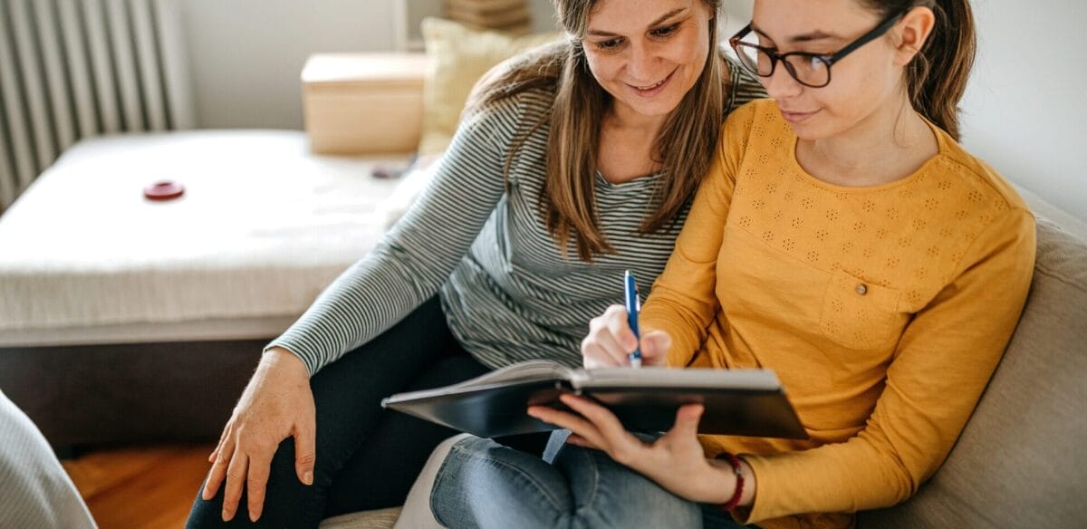 Two students tkaing notes at home
